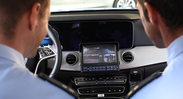 Zwei Polizeibeamte sitzen im Polizeiauto und schauen auf einen Bildschirm, der Aufnahmen des neuen Dashcam-Systems zeigt. Foto: zVg