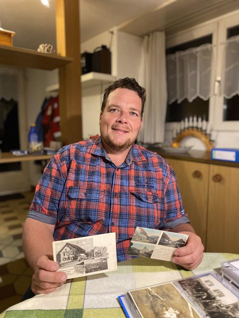 Auf dem Bild zeigt Marc Deiss zwei der wichtigsten Karten seiner Sammlung: zwei Postkarten aus dem heimatlichen Oberzeihen mit den Hauptsehenswürdigkeiten, dem Gasthaus zum Ochsen und der Kapelle. Foto: Sonja Fasler