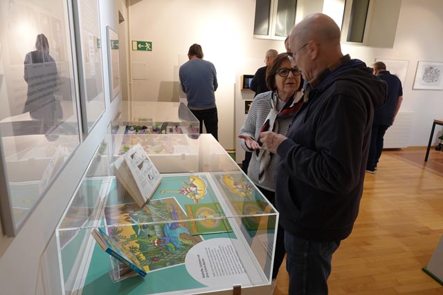 Besucher der Sonderausstellung an der Eröffnung vor einer Vitrine.