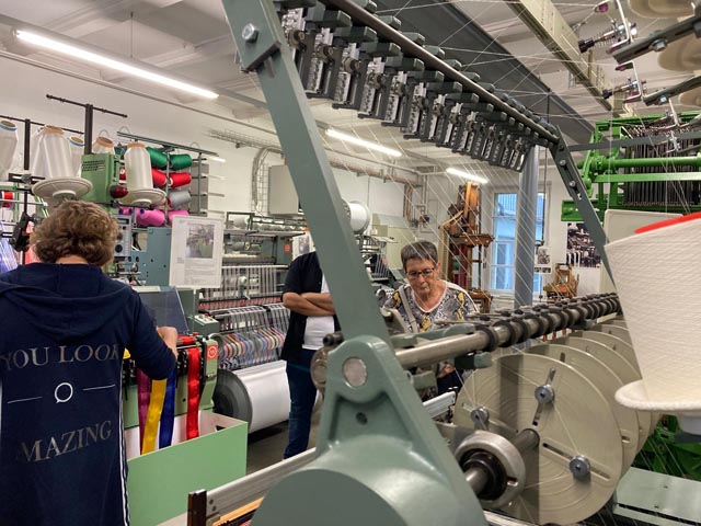 Gespannt lassen sich Freiwillige und Mitarbeitende der Tagesstätte die Geschichte der Bandweberei erklären. Foto: zVg