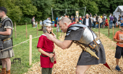  Ein Legionär hilft beim Justieren des Legionärshelms. Foto: © Augusta Raurica